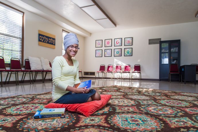 Student kneeling on floor with book