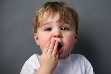 Child with hand over mouth