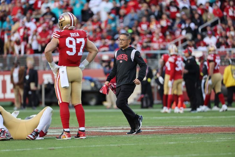 Manny Rivera stands on the 49ers field with football players