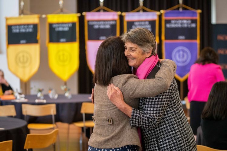 Maria Pallavicini hugs another faculty member