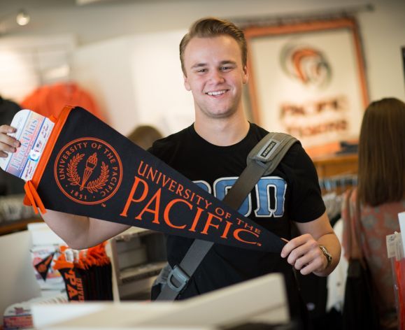 Smiling student holding Pacific pennant