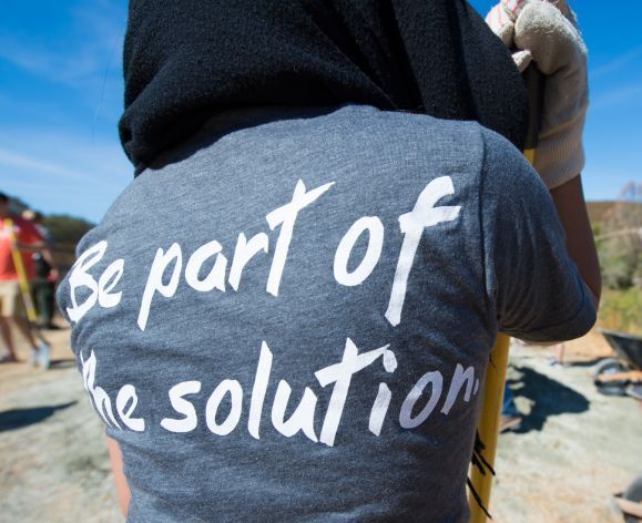 Pacific student volunteer wearing t-shirt that says, "Be part of the solution".