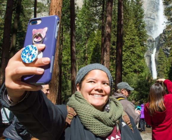 a student takes a selfie at a national park with a waterfall in the background